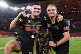 Rugby league player and his coach who is also his dad, poses for a photo with the grand final winner trophy