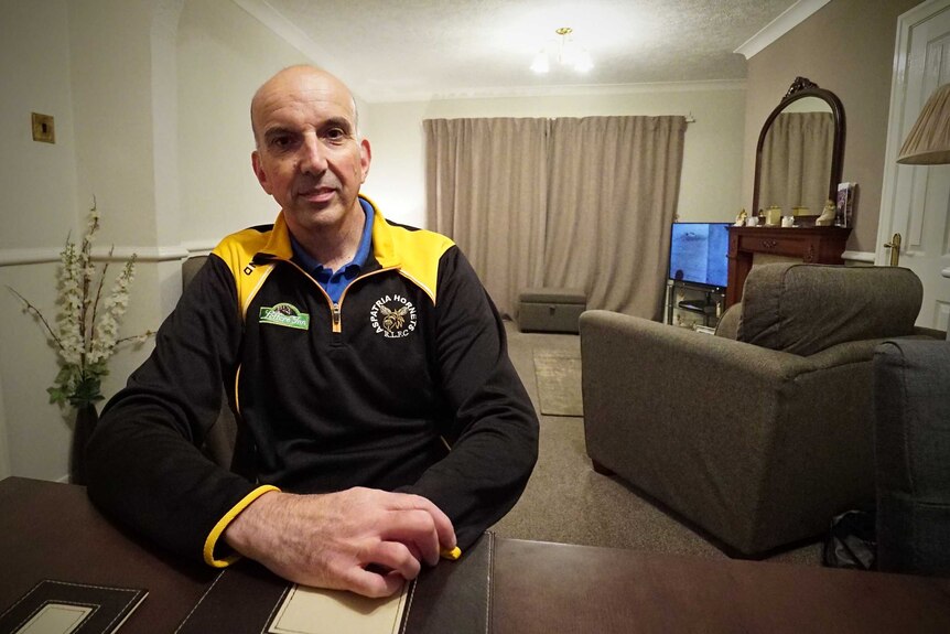 Mark Ridley sits at a table inside his home in Workington.