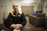 Mark Ridley sits at a table inside his home in Workington.