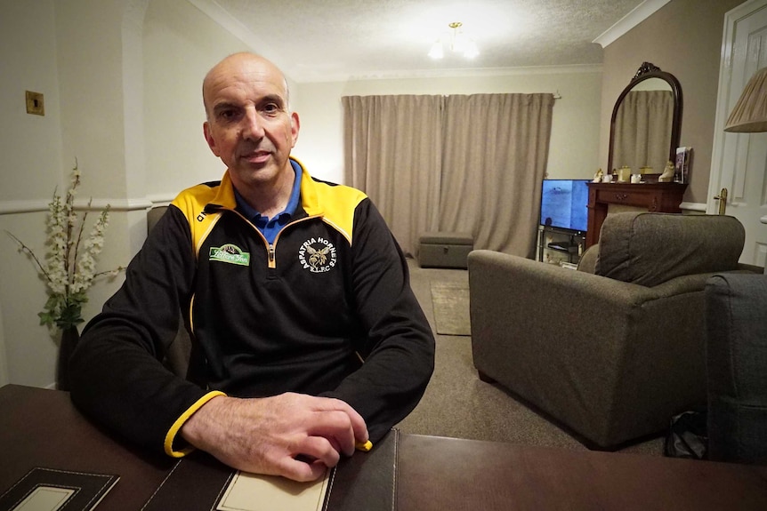 Mark Ridley sits at a table inside his home in Workington.