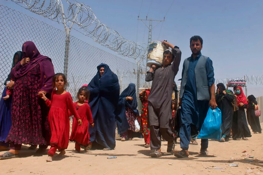 Afghans walk through a security barrier as they enter Pakistan through a common border crossing