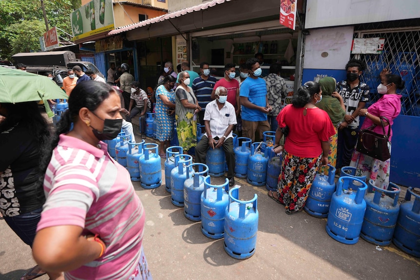 Una larga fila de botes de gas bordea la carretera mientras los habitantes de Sri Lanka esperan para comprar gas para cocinar de un vendedor en Colombo.