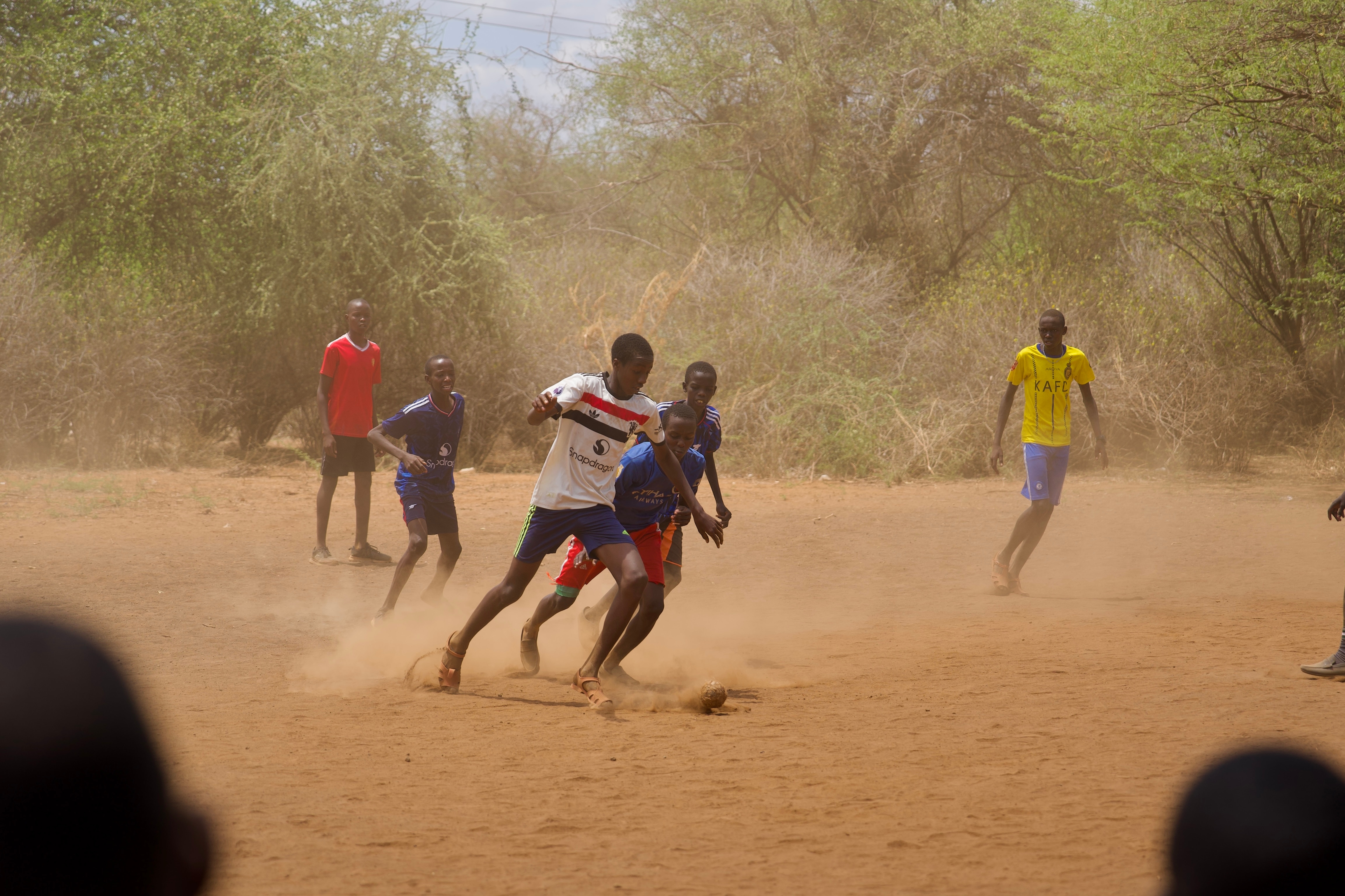 A group of Kenyan school students playing soccer with a rubber ball
