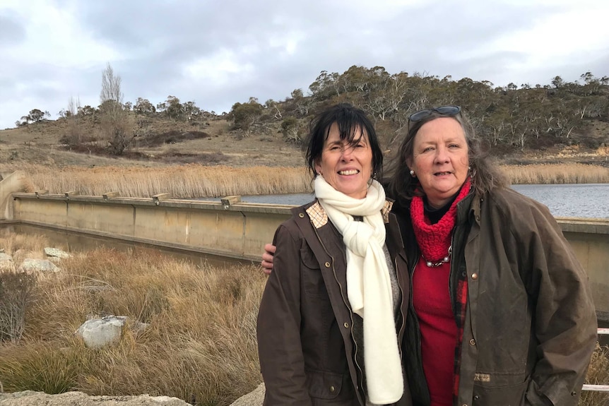 Two women standing in front of a weir in the NSW Snowy Mountains.