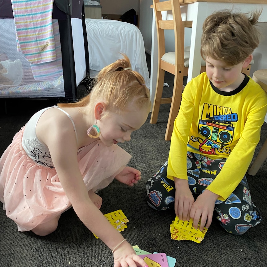 Two children playing cards on carpet