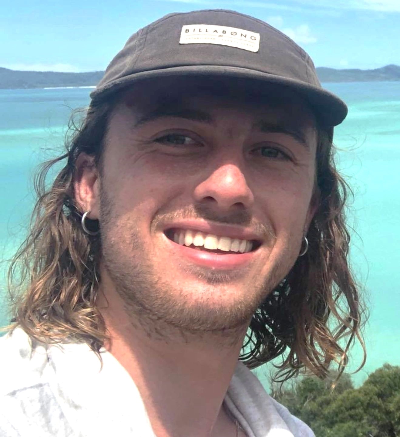 Charlie Woolley smiles near a beach.