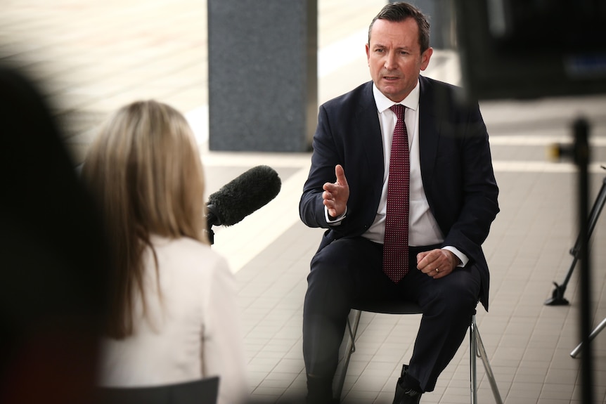 Mark McGowan sitting outside of WA Parliament and gesturing with his hand.