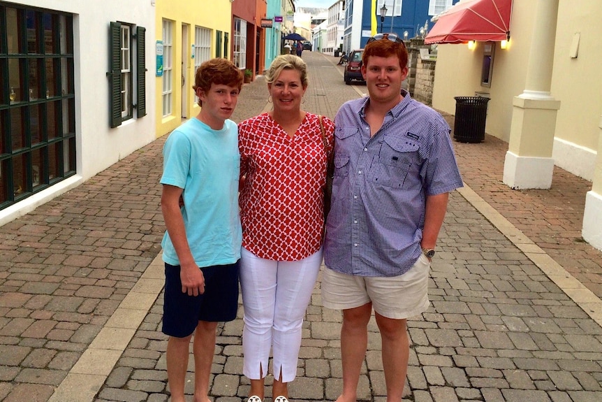 Maggie Murdaugh wearing a red shirt and white pants with her arms around her two sons 