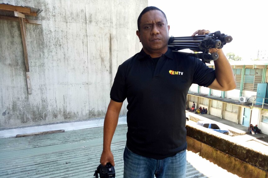 Scott Waide holds a camera on a roof in Papua New Guinea
