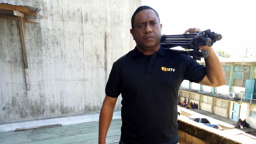 Scott Waide holds a camera on a roof in Papua New Guinea