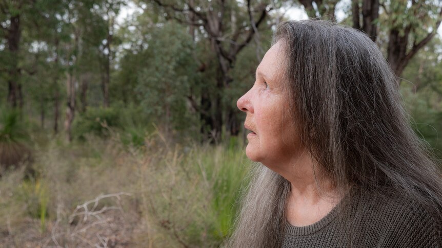 Woman with long grey hair in bushland