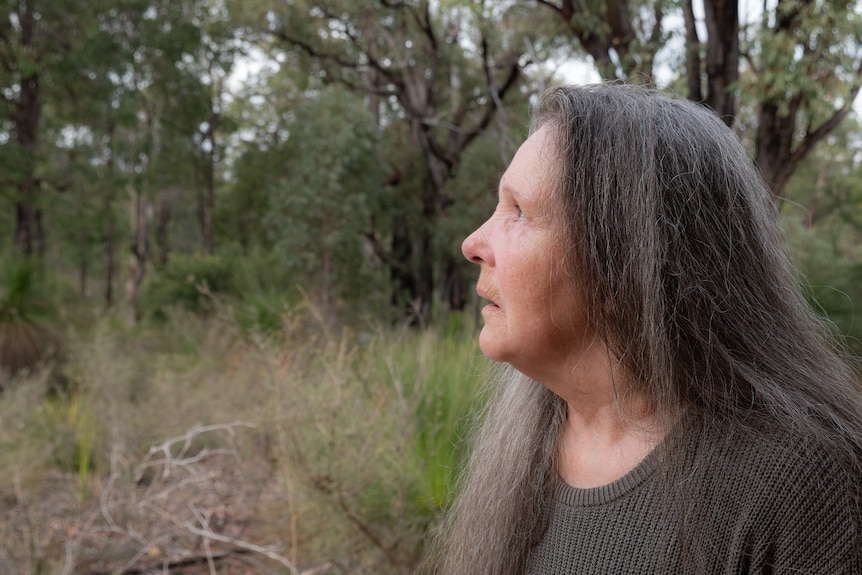 Woman with long grey hair in bushland