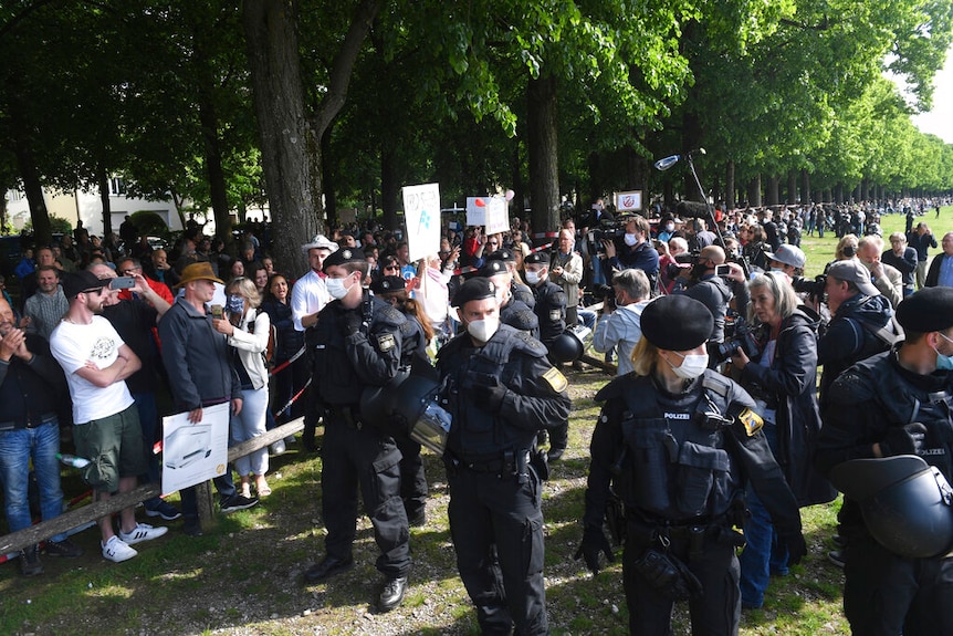 Protesters in Germany gathered at a park with police officers wearing face masks near by.