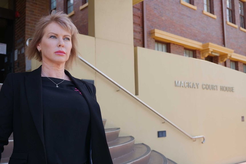 a woman walks down the stairs of a court house, looking into the distance