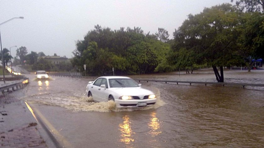 Cars cross a flooded 4-lane bridge on Morayfield Road at Caboolture.