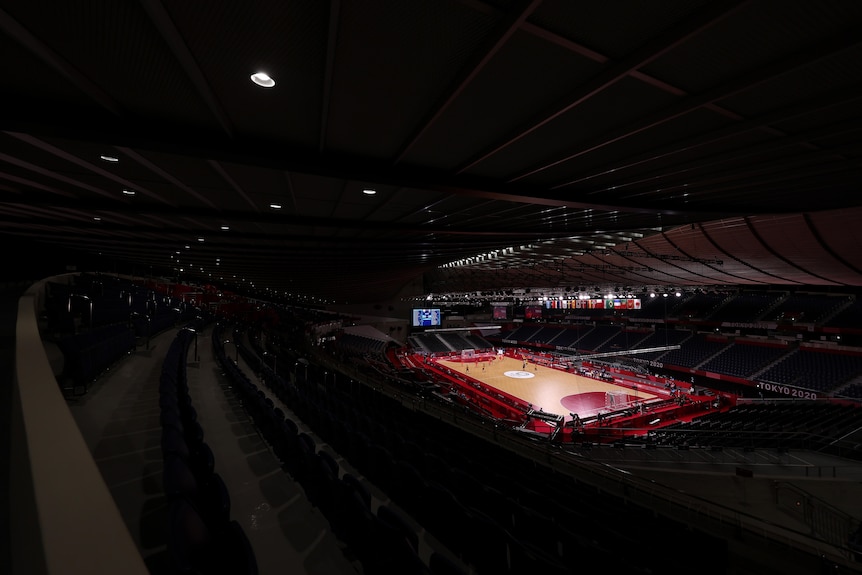 A darkened stadium is shown with a handball court lit up in the centre