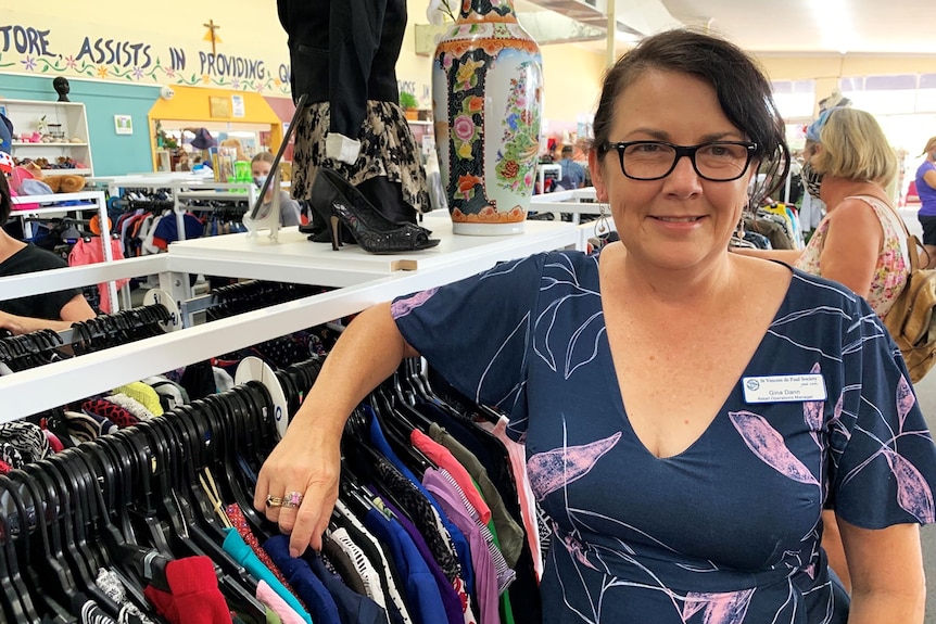 Gina Dann stands next some of the donated clothing for sale.