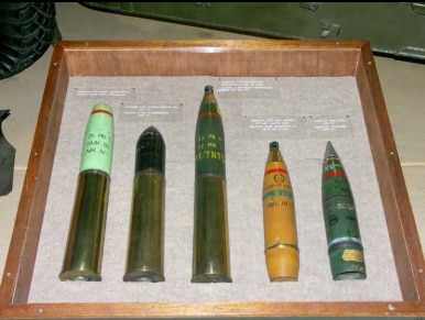 A case containing five artillery shells of various size.