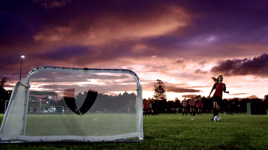 Girls training with a small goal and beautiful sunset behind.