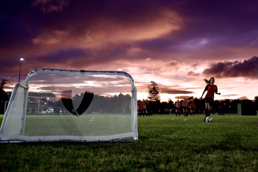 Girls training with a small goal and beautiful sunset behind.