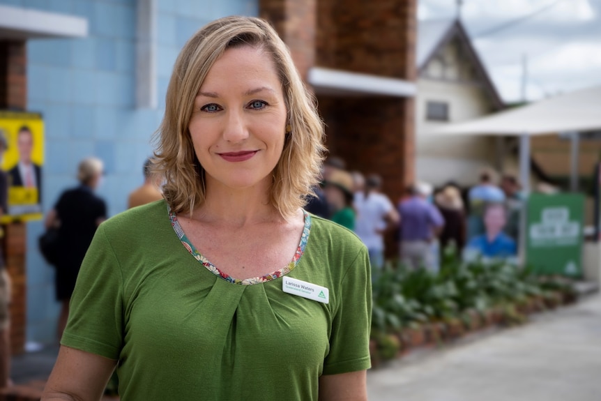 A woman with shoulder-length blonde hair, smiling, outside.