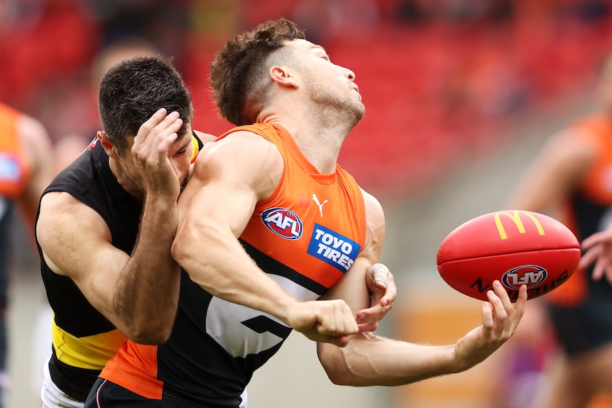 Toby Greene tries to get a handball away as Trent Cotchin tackles him from behind