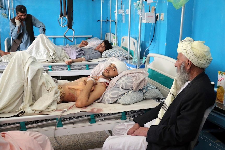 Afghans lie on beds at a hospital after they were wounded in the deadly attacks outside the airport