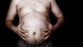 A man grabbing his overweight belly