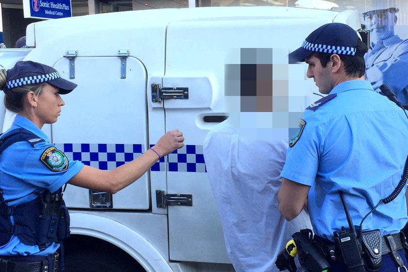 Police escort a student to a police van outside Arthur Phillip High in Sydney.