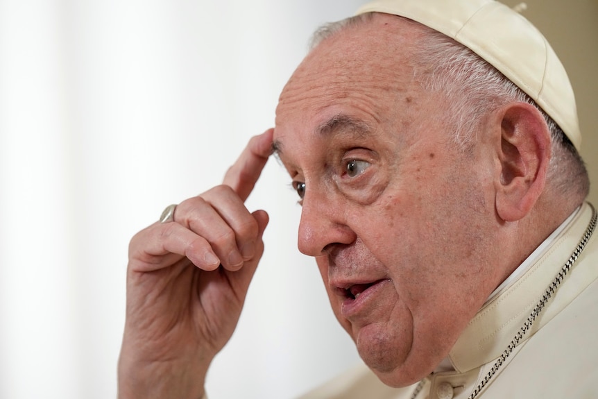 A close-up of Pope Francis in a cream cap. 
