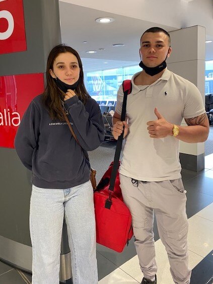 Brother and sister standing in an airport.