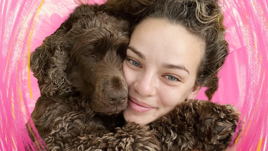 a girl with blonde curly hair cuddles a fluffy dog