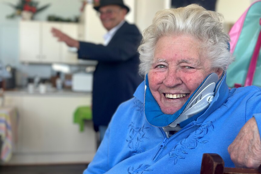 A grey haired woman smiles as Liverpool Plains Shire Council Mayor Doug Hawkins speaks in the background. 