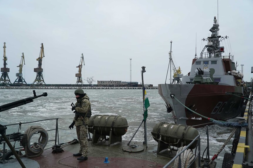 A Ukranian serviceman boards a coast guard ship in icy waters in the Sea of Azov