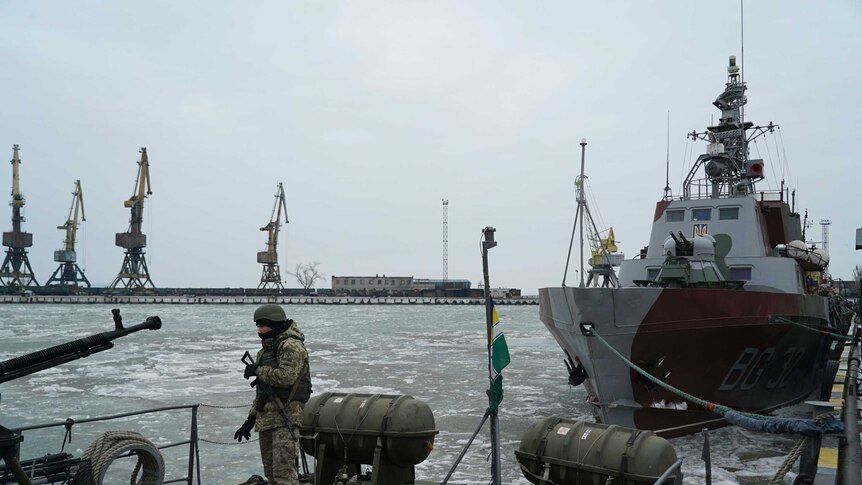 A Ukranian serviceman boards a coast guard ship in icy waters in the Sea of Azov