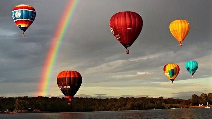 A rainbow and hot air balloons Canberra's Lake Burley Griffin.