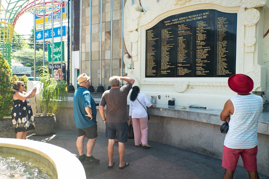 Orang-orang melihat ke dinding bertuliskan nama-nama mereka yang tewas dalam bom Bali.