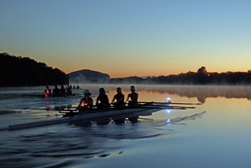 Rowers on a river at dawn