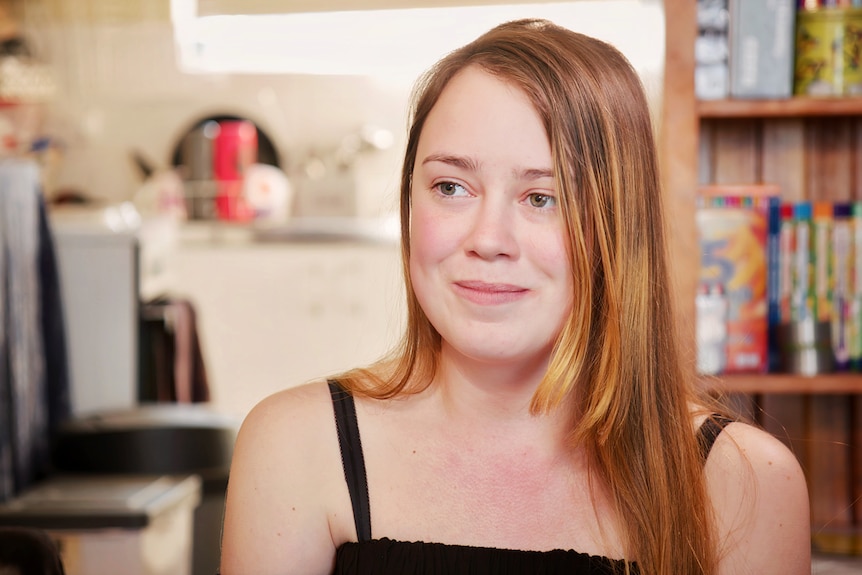 A teenage girl looks past the camera, smiling.