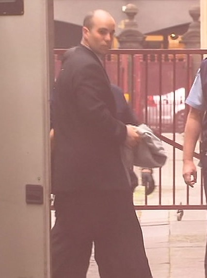 Thomas Kelson, wearing a suit, walks from a prison van to a courtroom door.