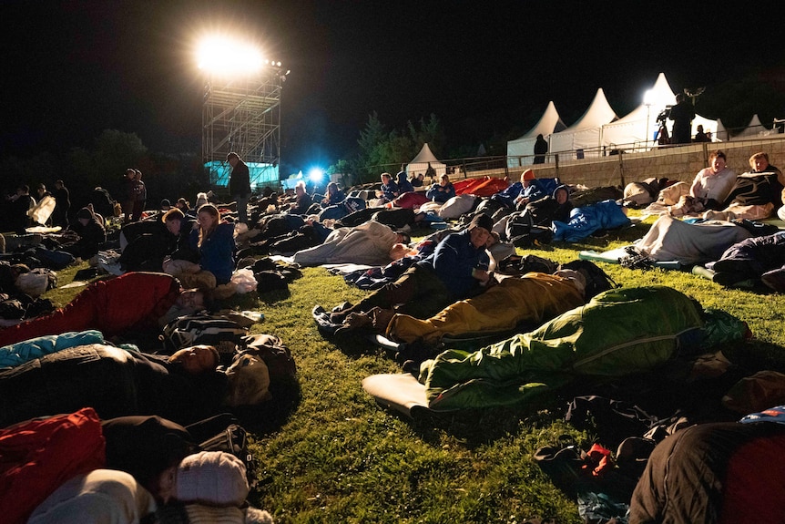 People in the dark outside in sleeping bags.