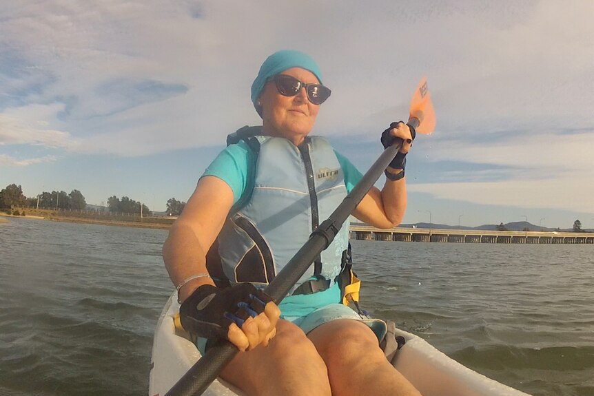 A woman in her 60s paddling a kayak.
