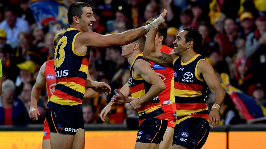 Both smiling, Taylor Walker and Eddie Betts high-five as they run past each other.