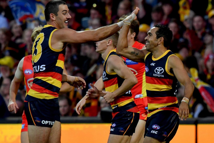 Both smiling, Taylor Walker and Eddie Betts high-five as they run past each other.