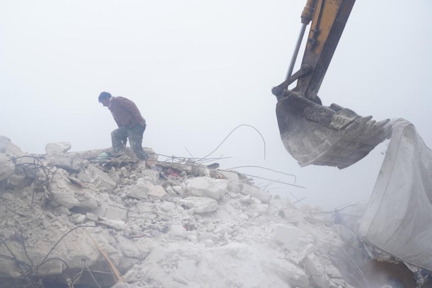 An image of a excavator at the site of a collapsed building.