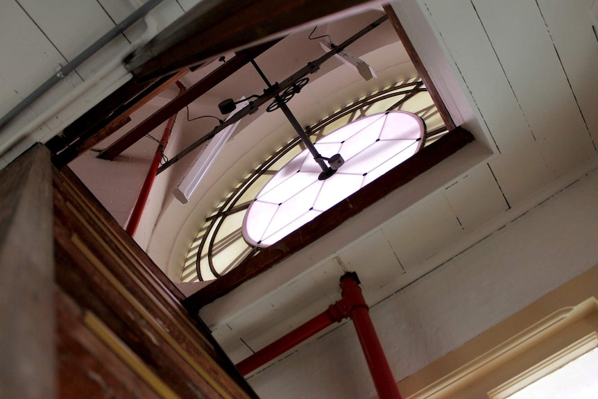 A clock face in a tower, with weatherboards around it.
