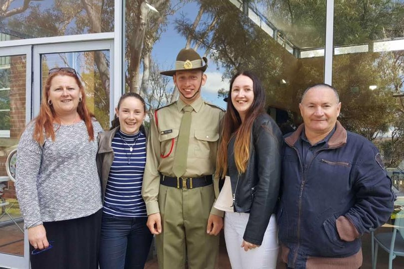 A young soldier stands with his family. 