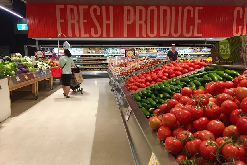 A mostly empty Coles supermarket, its vegetable section laden with produce.