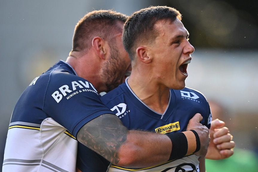 A North Queensland Cowboys NRL player screams out as he celebrates a try with a teammate.