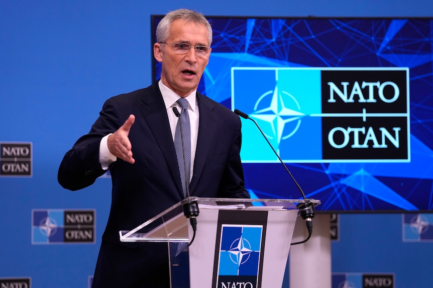 Man in a suit gives a speech from a podium.